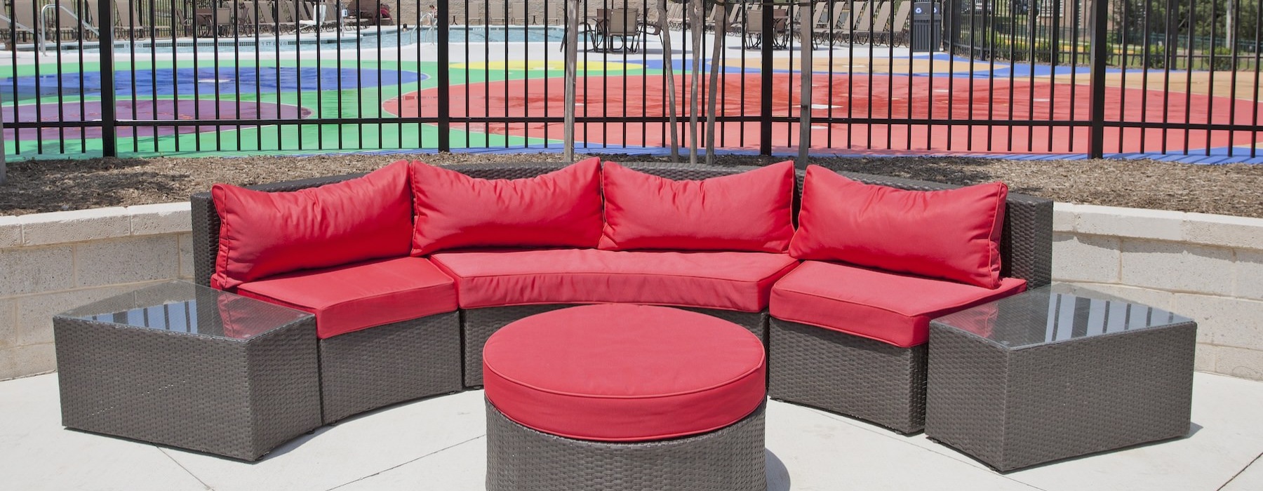 a red couch in front of a fence and a tree