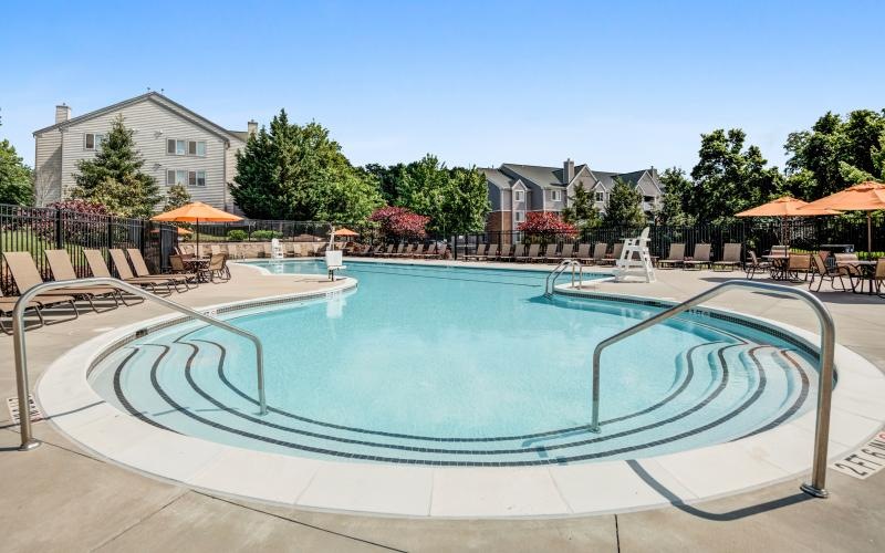 a pool with a deck and umbrellas by it