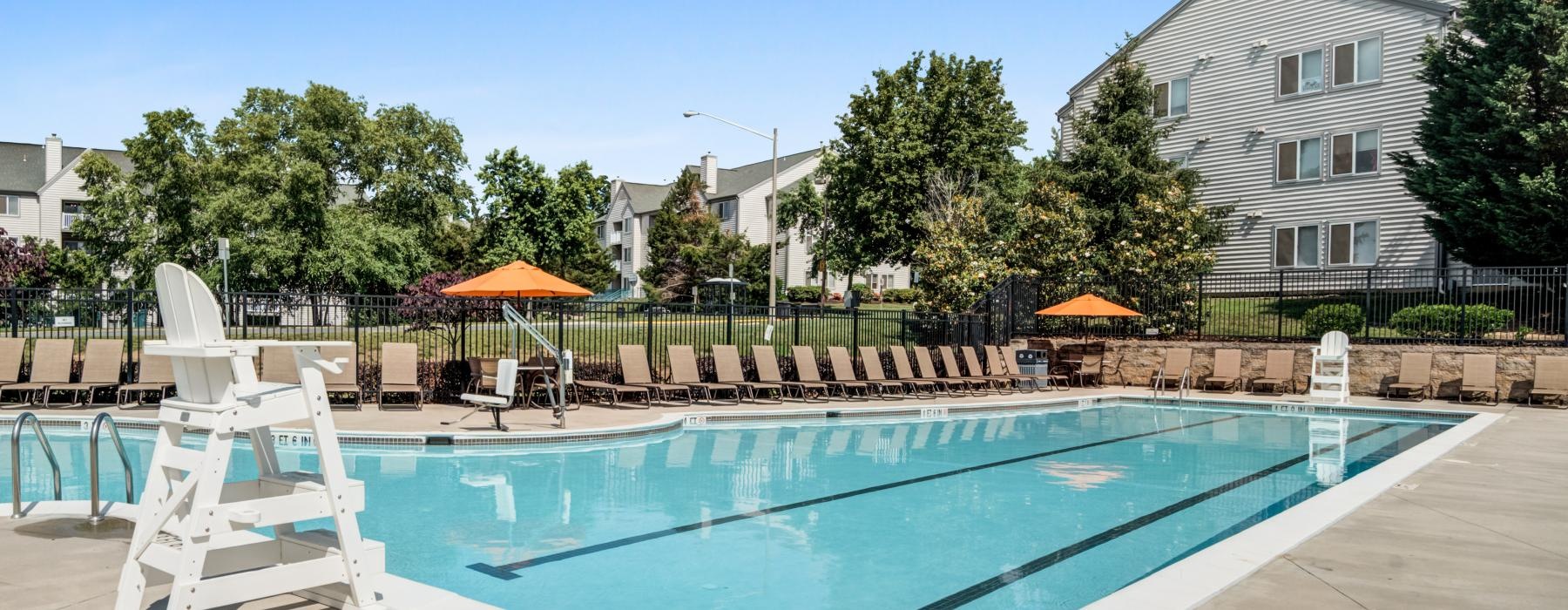 a swimming pool with chairs and umbrellas by a house